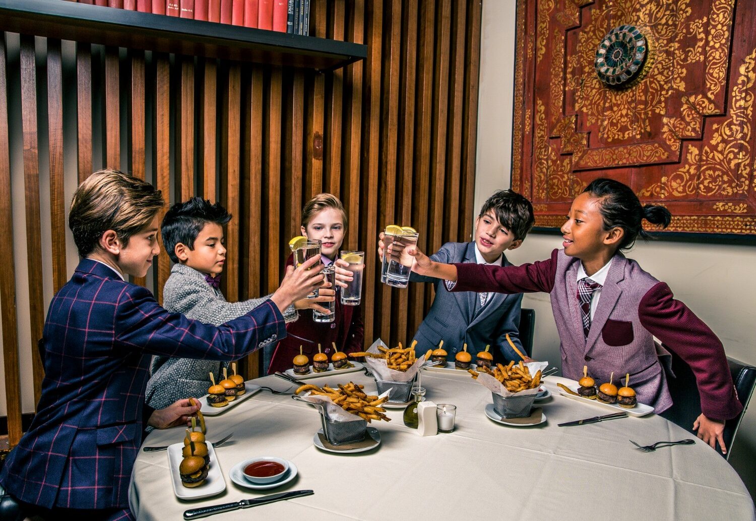 Boys toasting at a dinner in Isaac Mizrahi looks