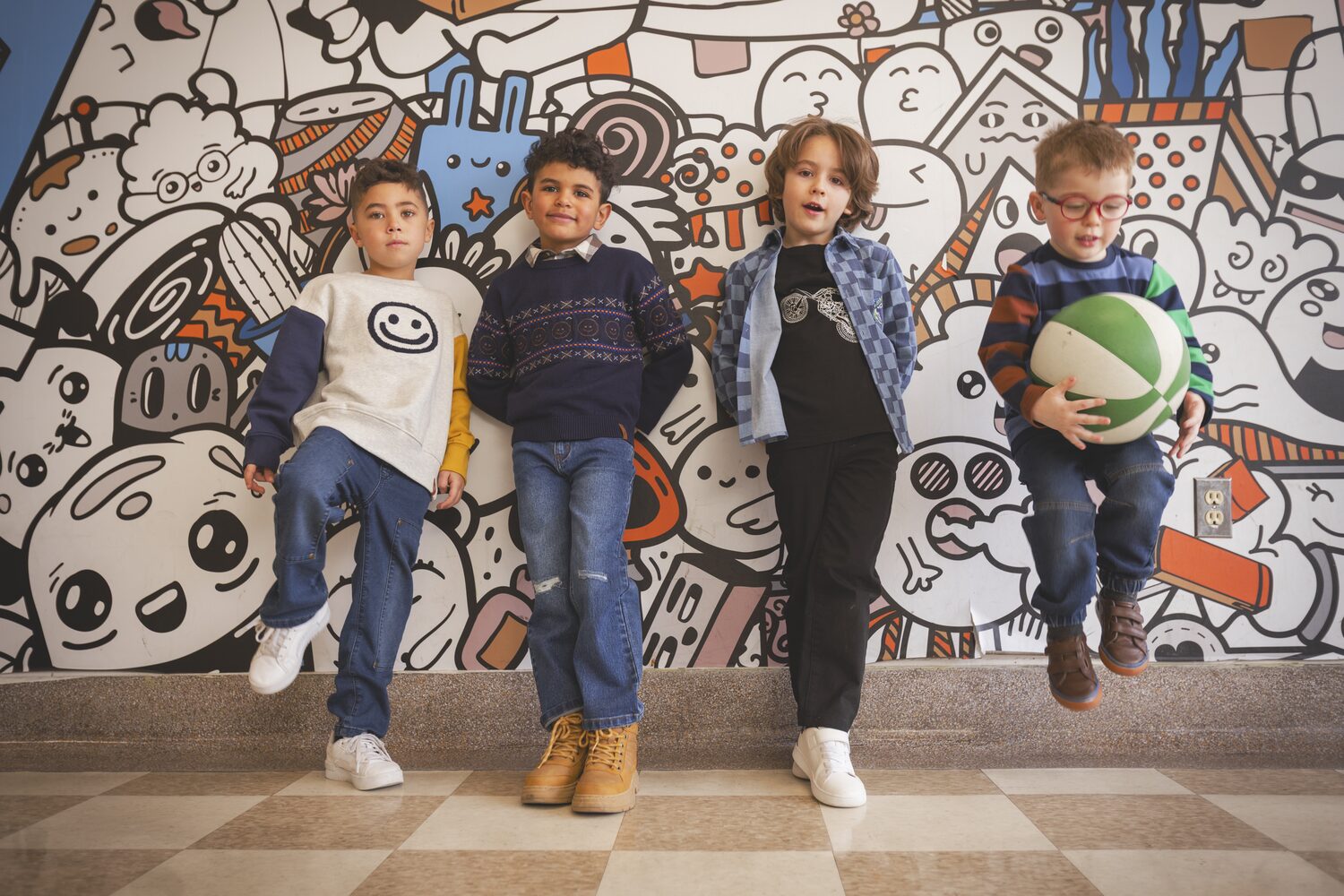 Four kids in Deux par Deux against a doodle wall