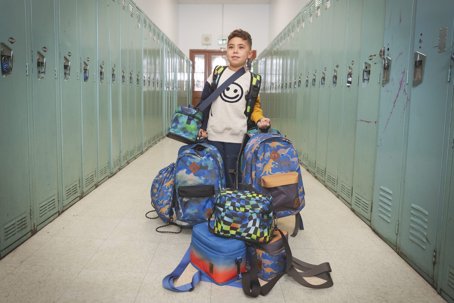 Boy in a locker hallway with Deux par Deux backpacks