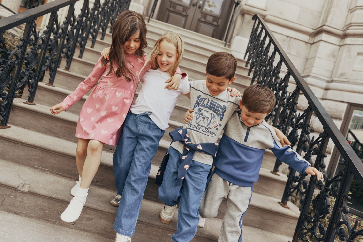 Four kids in Miles The Label knits and denim walking down stone steps
