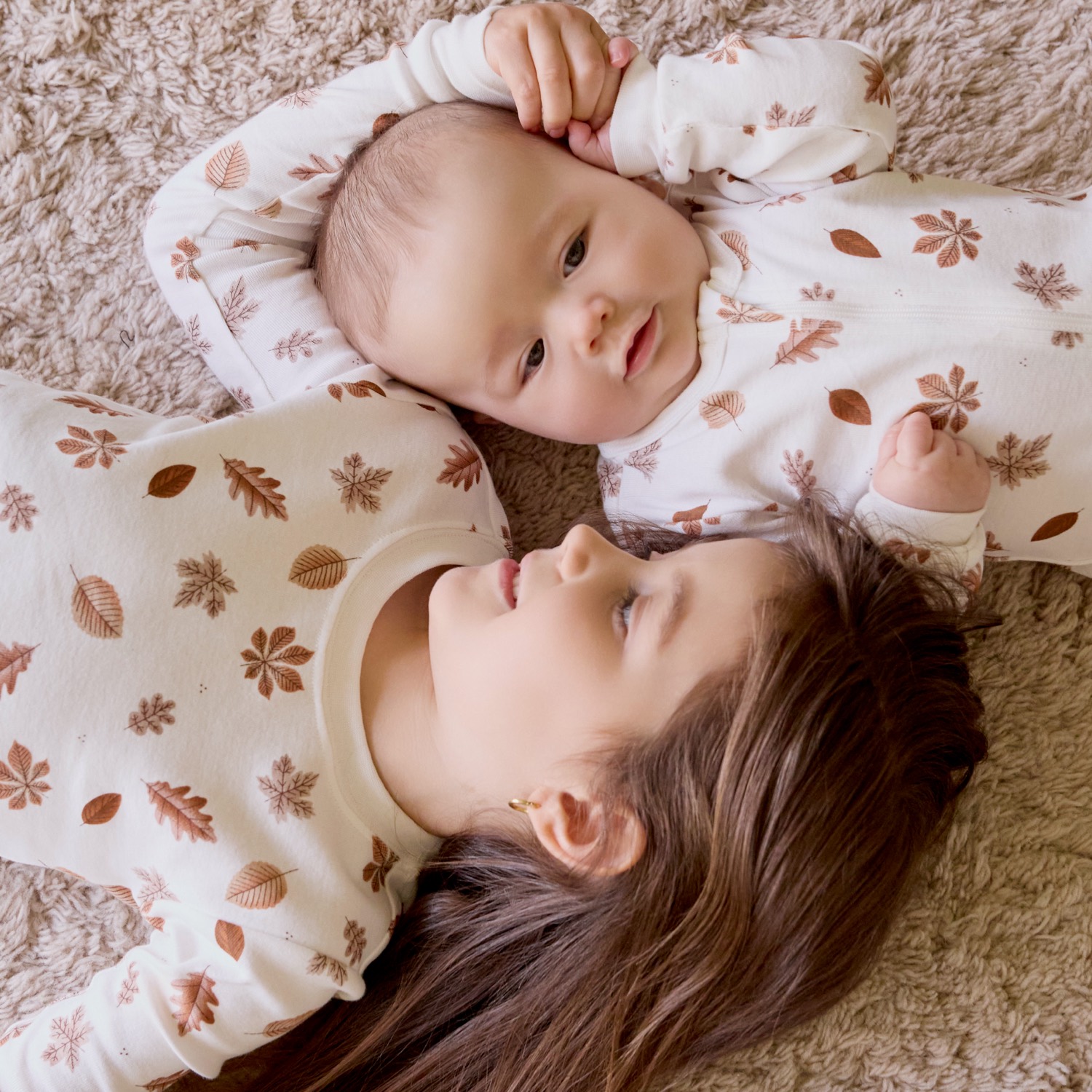 Baby and child lying head to head in Petit Lem leaf-print pyjamas