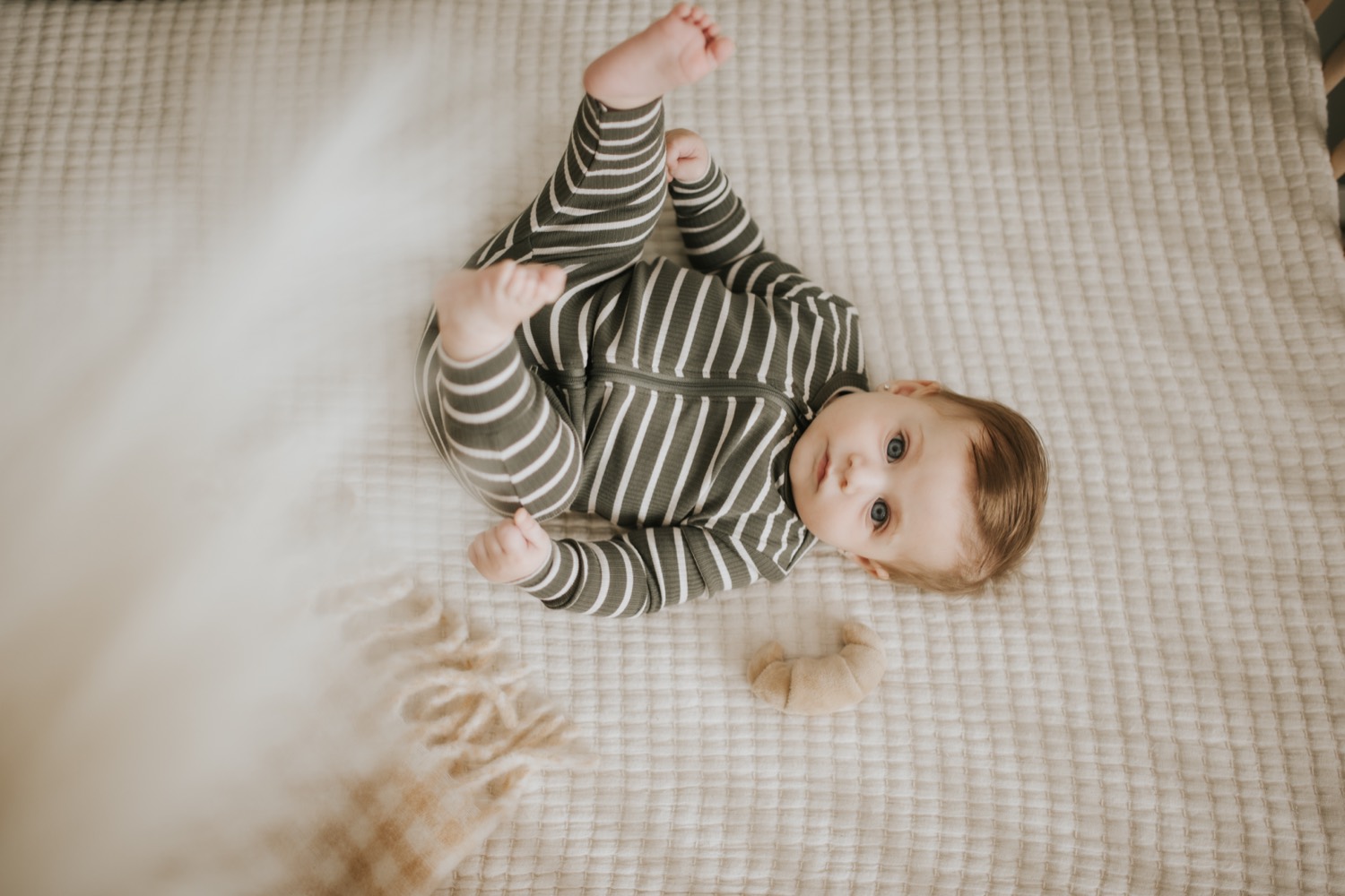 Baby in a Petit Lem green-and-white striped zip sleeper