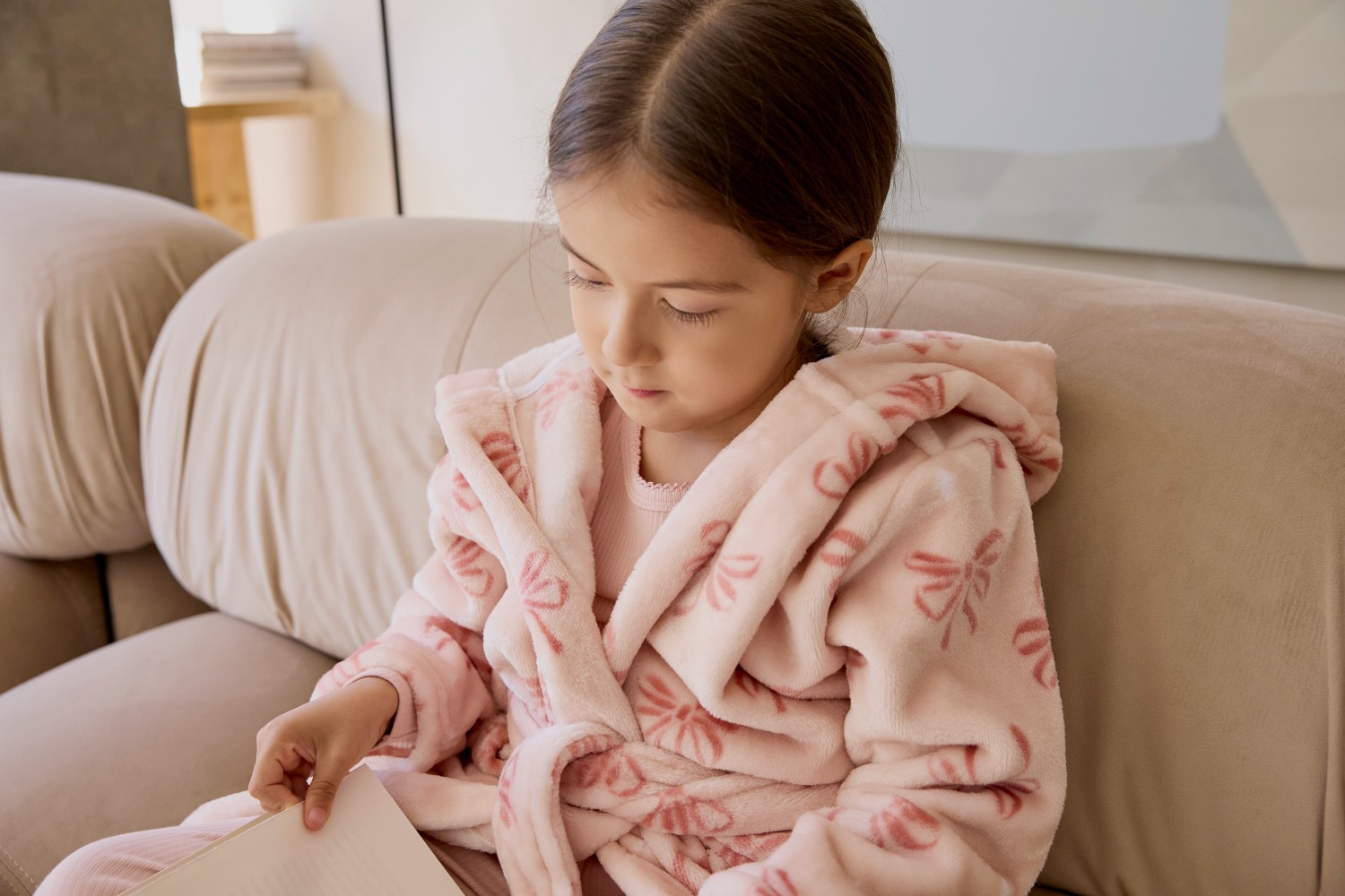 Girl in a Petit Lem pink bow-print fleece robe